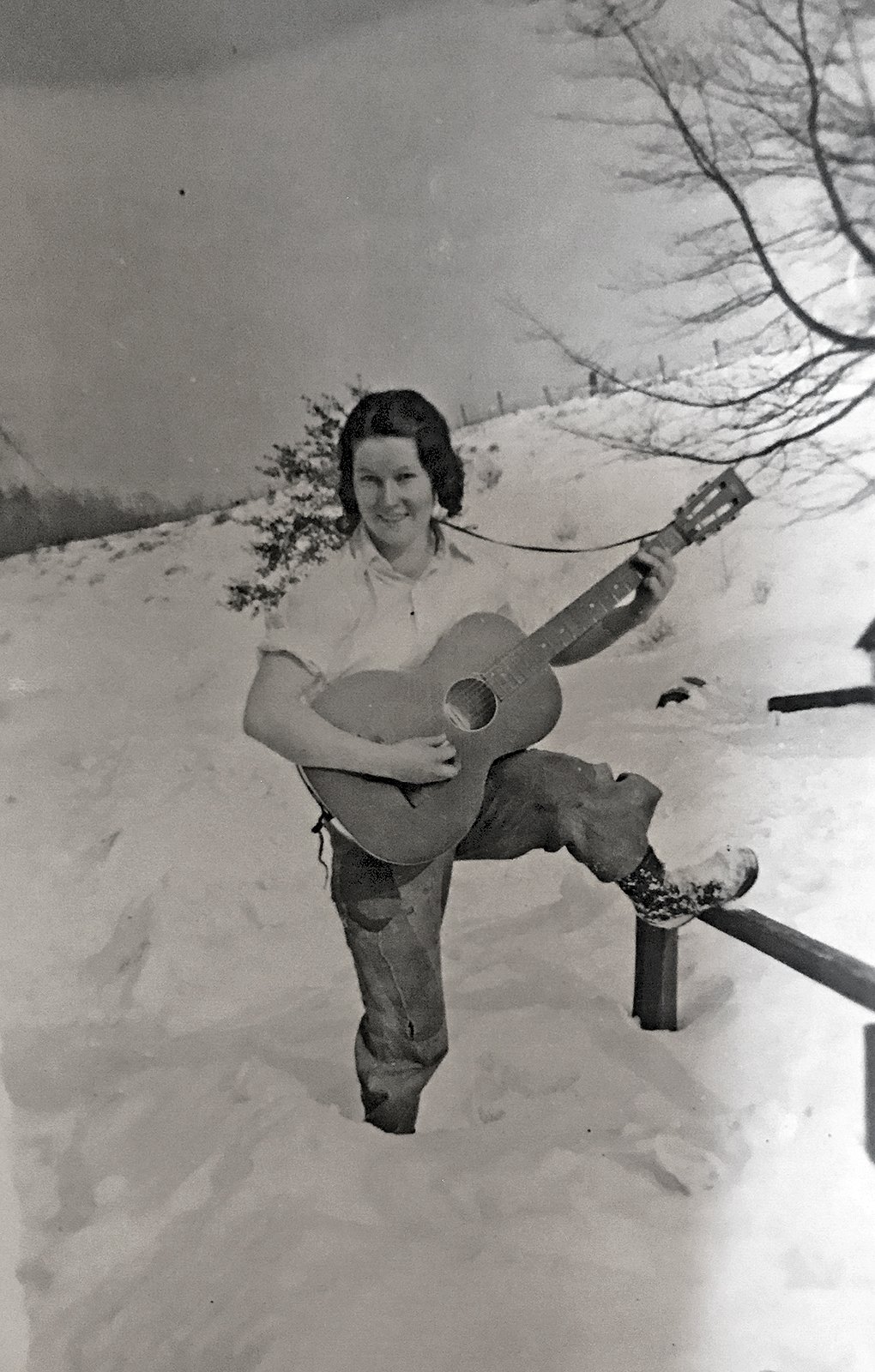 Maria Yohe playing guitar in the snow on the family farm, Pennsylvania, c. 1940s.